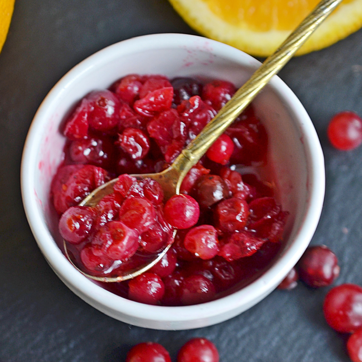 Cranberry orange sauce in a bowl served with a golden color spoon.