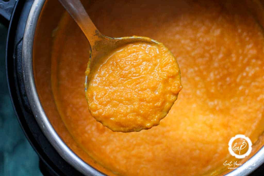 Serving carrot and leak soup with a serving spoon.