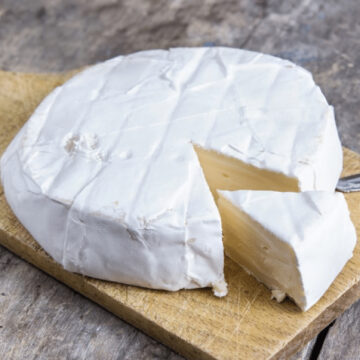 Fresh brie cheese on wooden board.