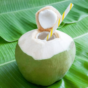 Fresh green coconut with a straw in it.