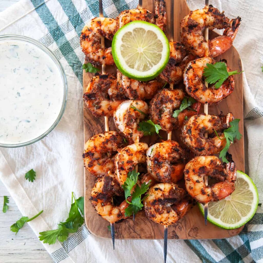 Grilled blackened shrimp on a wooden board.