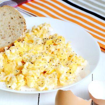 Scrambled eggs served with a bread slice on a plate.