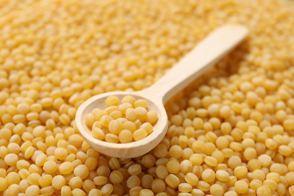 Can You Freeze Couscous - Wooden spoon on uncooked ptitim background, close up
