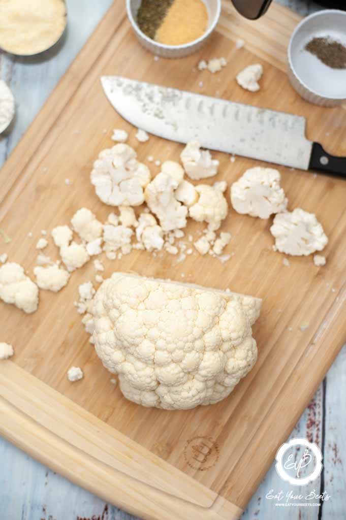 chopping cauliflower on wooden board.
