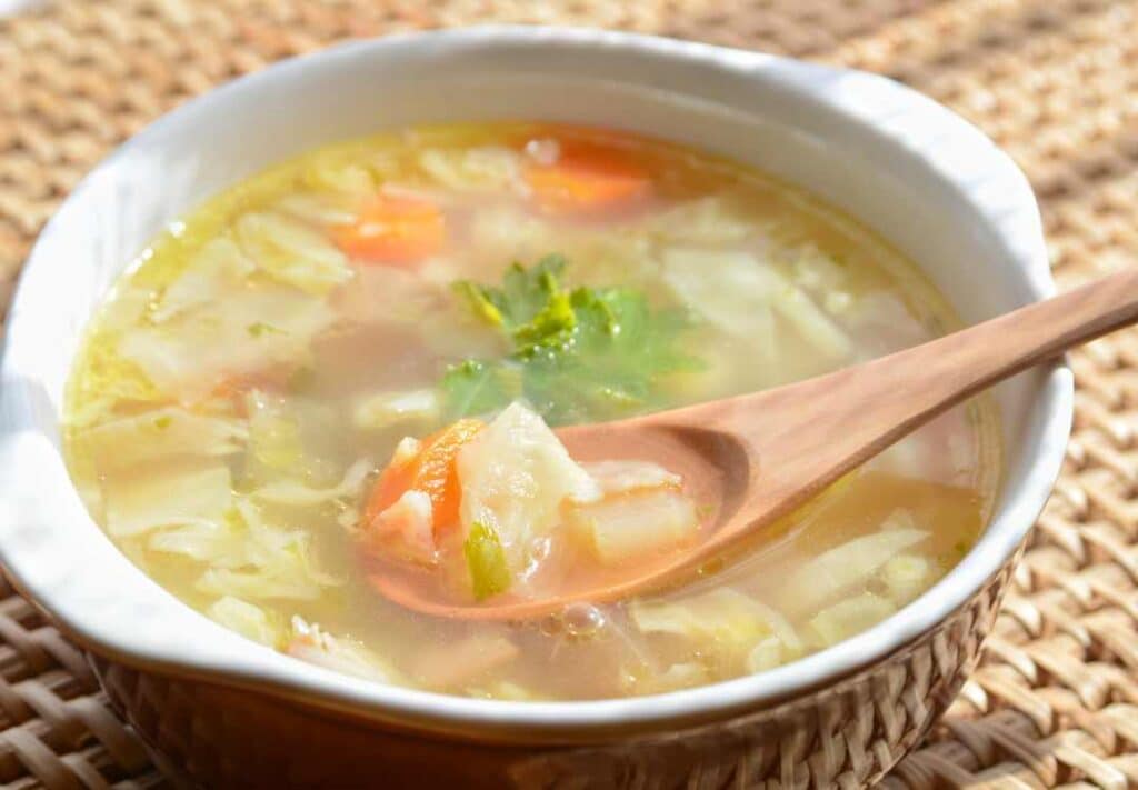 cabbage soup in a bowl with a wooden spoon.