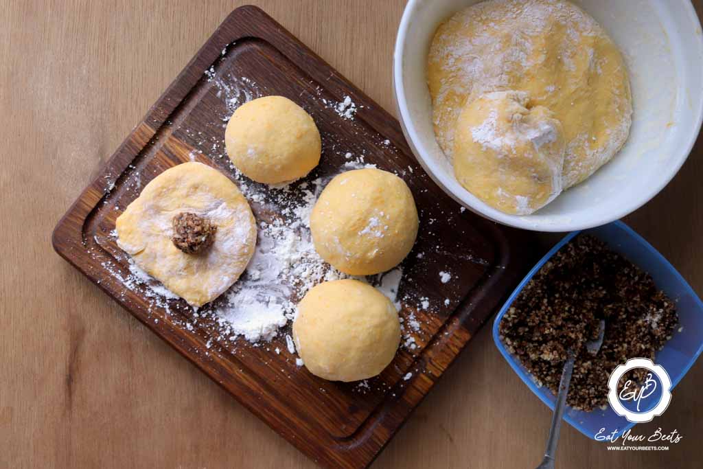 Filling small pieces of dough with grinded nuts and chocolate chips.