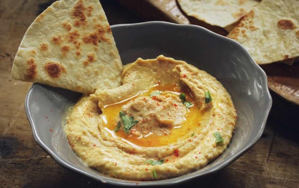 Hummus on a plate garnished with oil and basil.