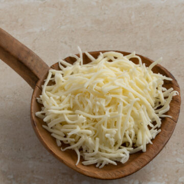Shredded cheese on a wooden spoon.