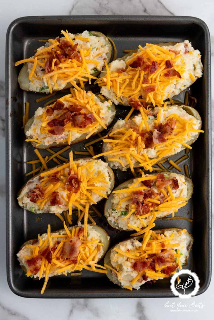 topping stuffed potatoes with cheddar cheese.