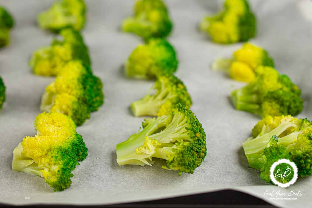 Broccoli pieces on a parchment paper.