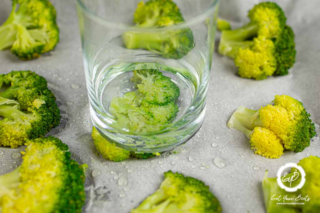 Smashing each broccoli with a glass cup.