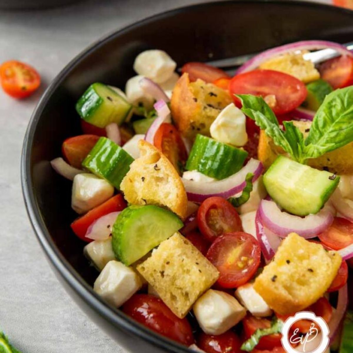 Greek Panzanella with Mozzarella in a black bowl.