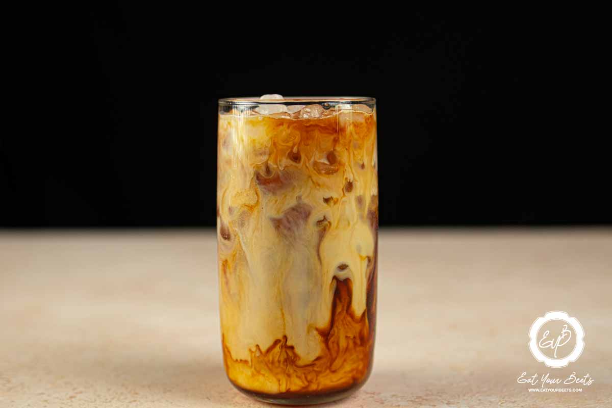 Brewed coffee, hazelnut syrup, oat milk, and ice in a glass.