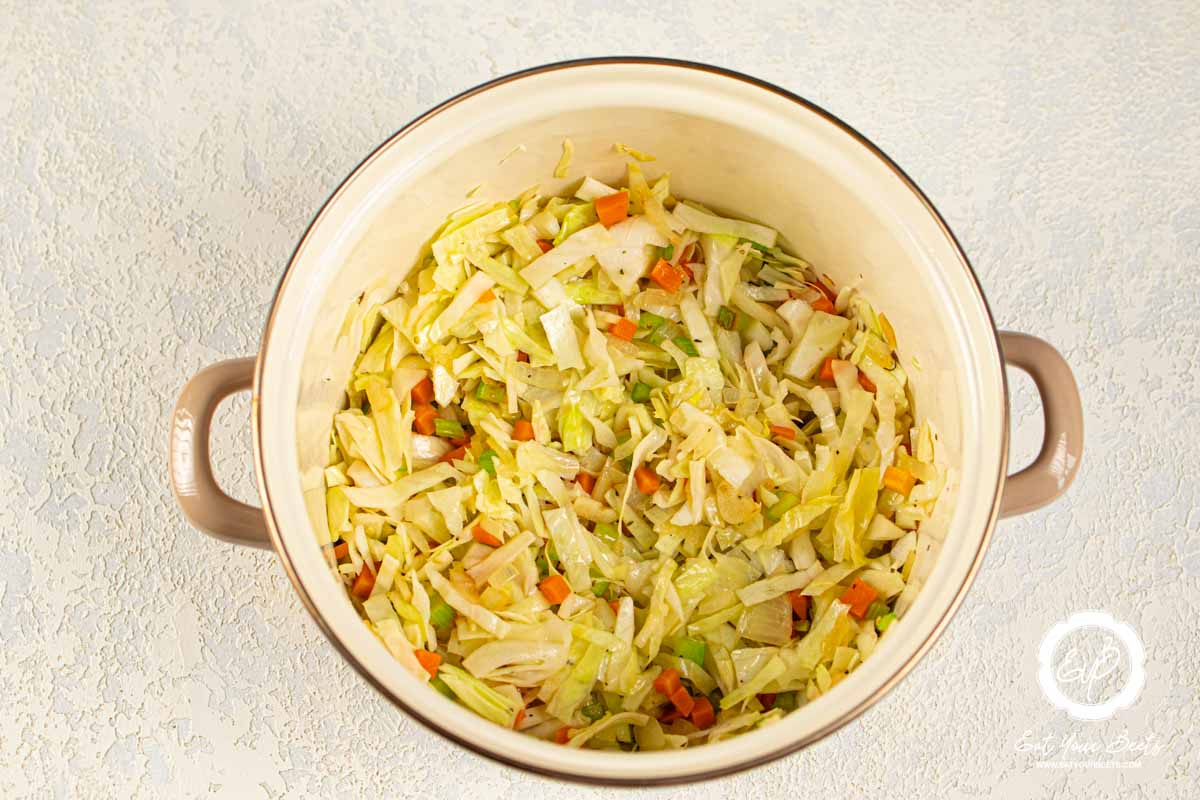 Sautéing onions, garlic, carrots, and celery in a pan.