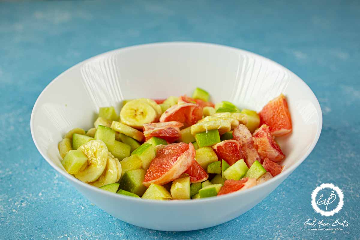 Chopped grapefruit, apple, and banana in a bowl.