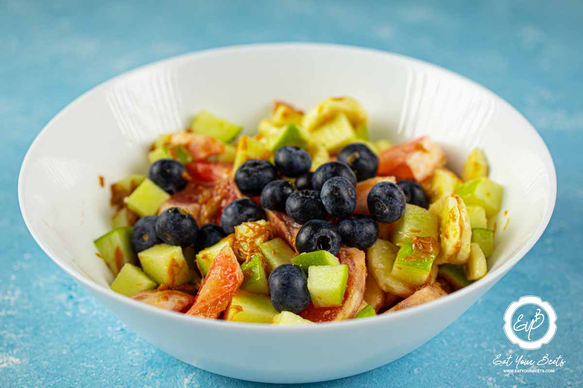 Blueberries, grapefruit, apple, and banana in a bowl.