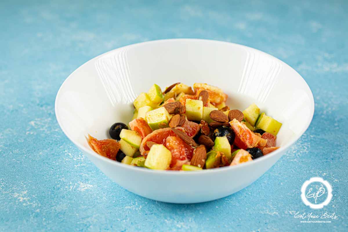 Almonds, blueberries, grapefruit, apple, and banana in a bowl.
