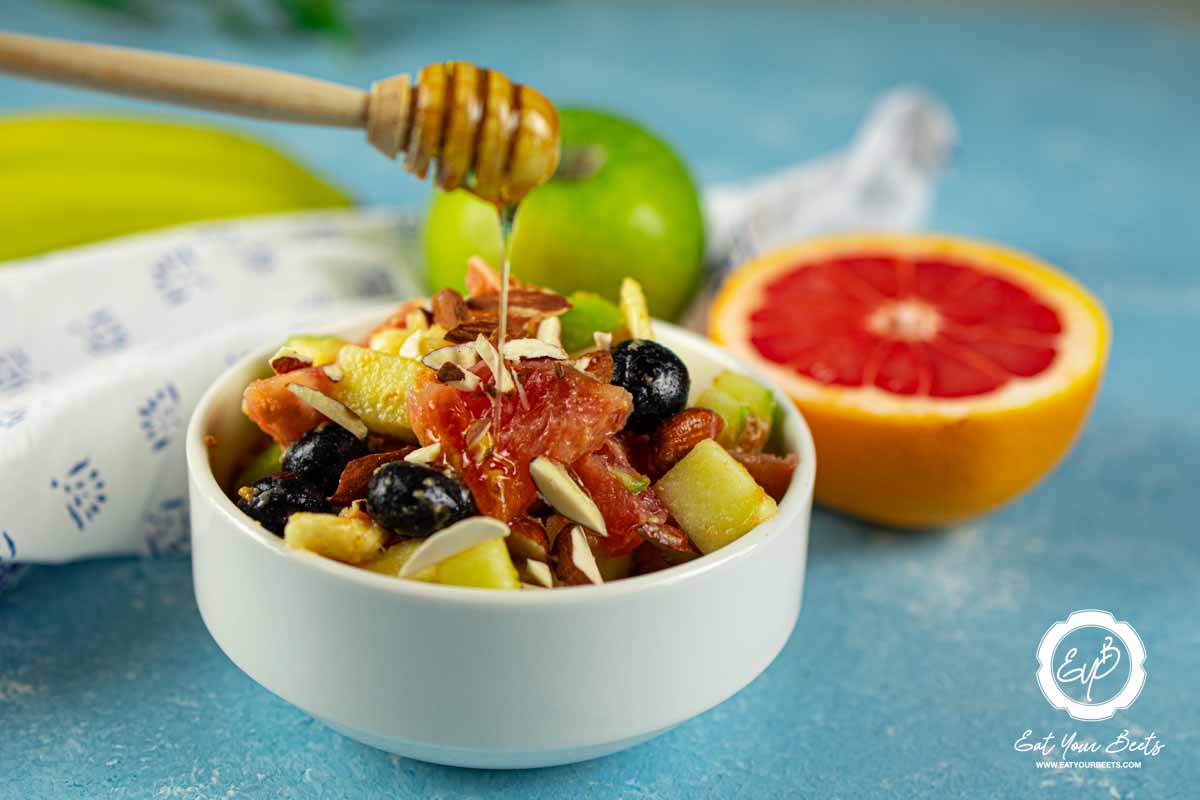 Pouring honey over grapefruit apple salad.