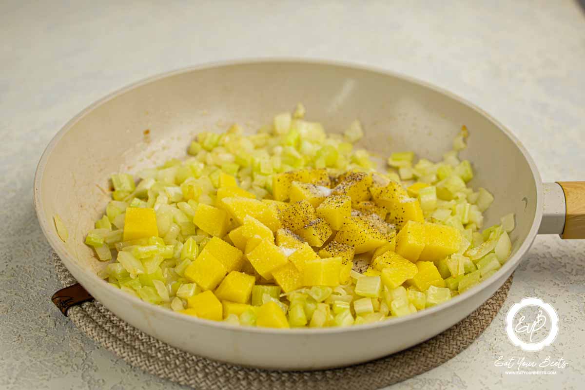 Cooking chopped onion and potato in a frying pan.