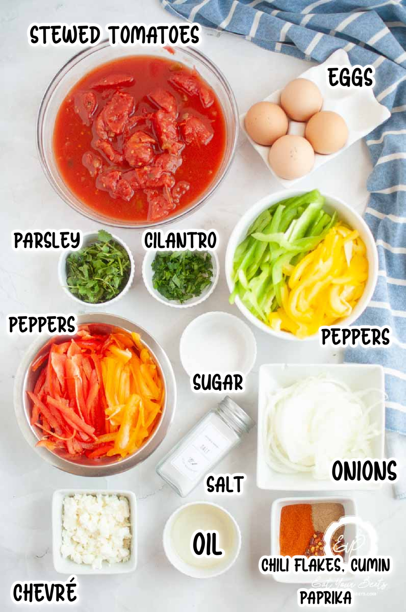 Ingredients for shakshuka with chevre, oil, chili flakes, onoins, peppers ,eggs and herbs.