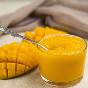 mango puree in a bowl and sliced mango on the side.