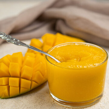 mango puree in a bowl and sliced mango on the side.