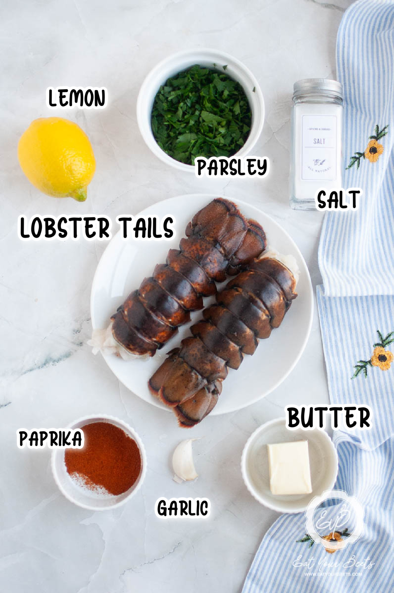 ingredients for lobster tails, lobster, parsley, garlic clove, lemon, butter, paprika, salt and pepper.