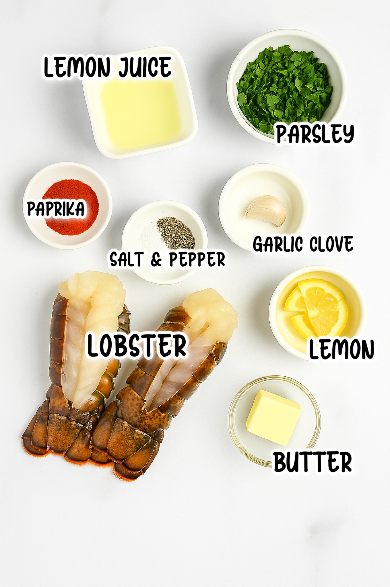 ingredients for lobster tails, lobster, parsley, garlic clove, lemon, butter, paprika, salt and pepper. 