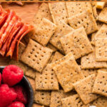 Einkorn Crackers on a cheeseboard with salami and raspberries.