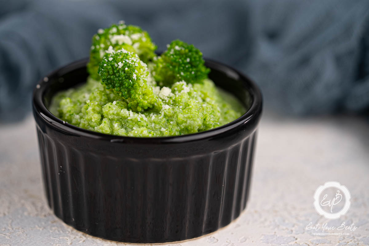 Broccoli puree in a ramekin topped with broccoli florets.