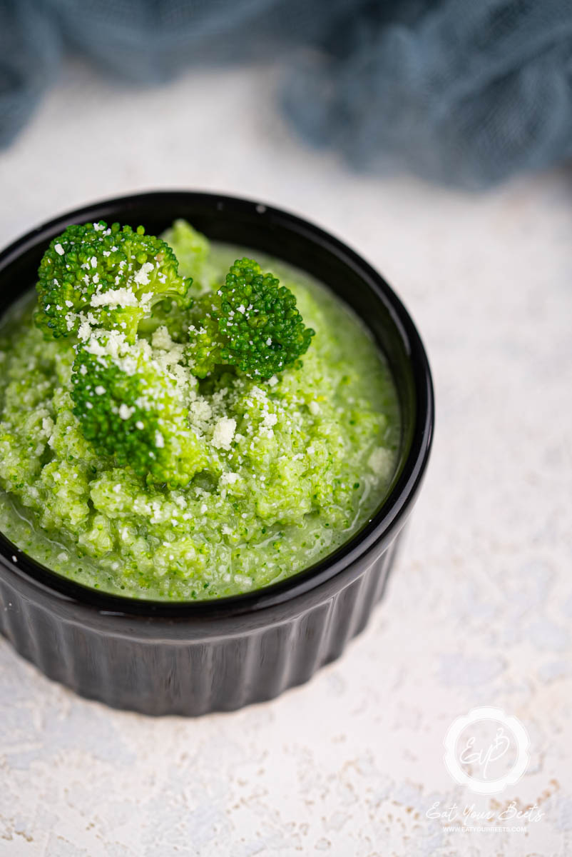 Broccoli puree in a ramekin topped with broccoli florets.