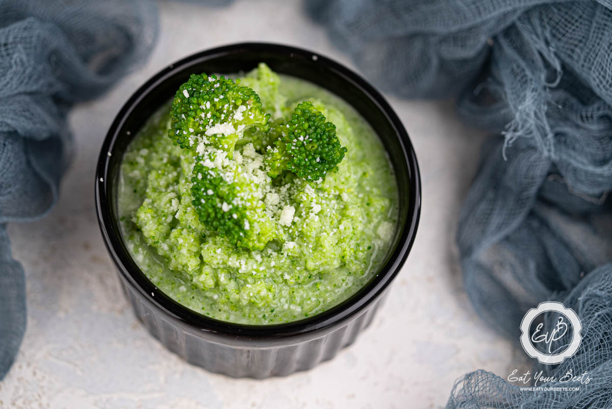 Broccoli puree in a ramekin topped with broccoli florets.